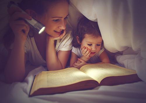 Kids reading under blanket with flashlght image